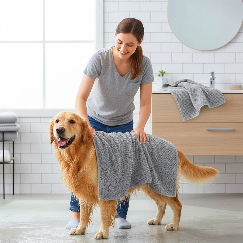 Frau trocknet ihren Golden Retriever im Badezimmer mit einem grauen Hundehandtuch ab