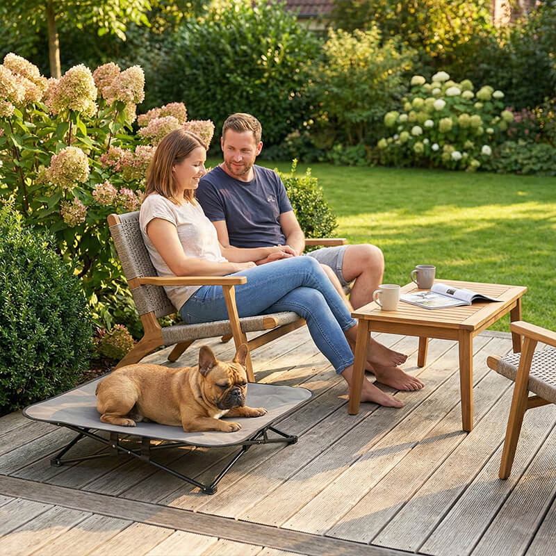 Outdoor Hundebett auf der Terrasse mit ruhendem Hund neben seinen Besitzern im sonnigen Garten.